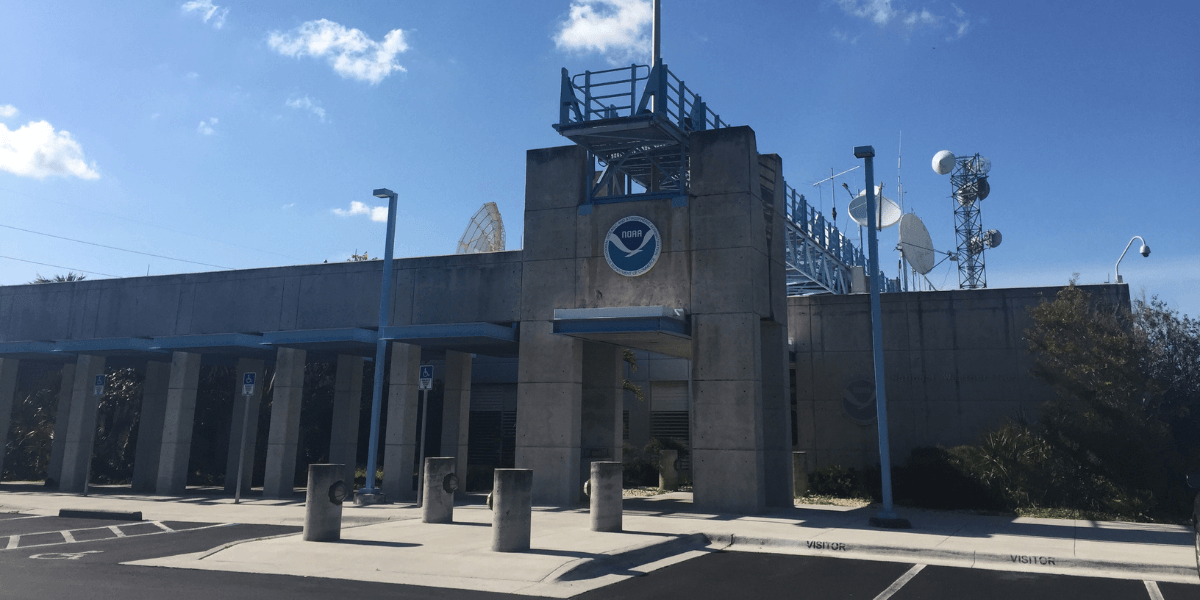 Concrete building with NOAA logo, radar dishes, and a clear blue sky
