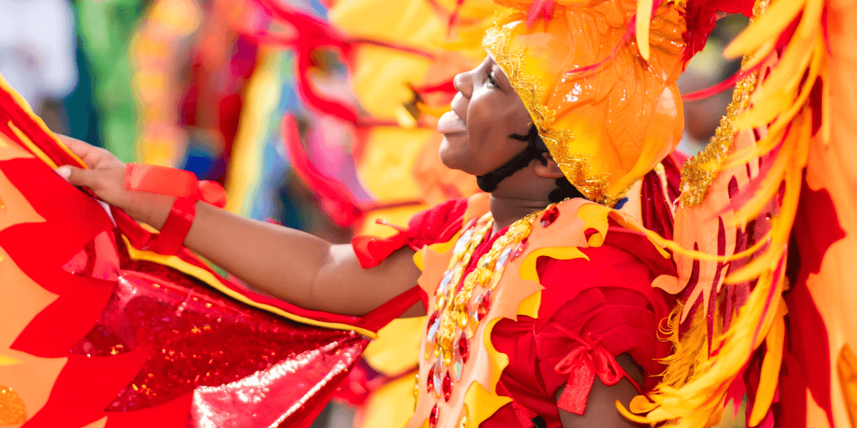 Child in vibrant orange and red costume, joyfully participating in a colorful parade