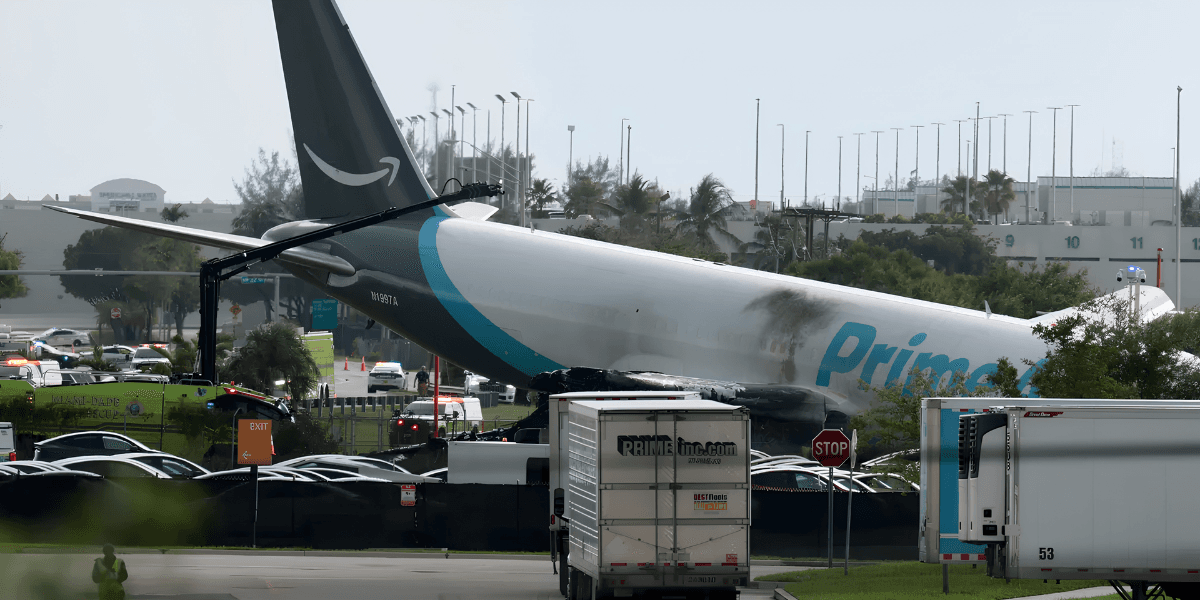 A damaged cargo plane rests on the ground with emergency vehicles nearby