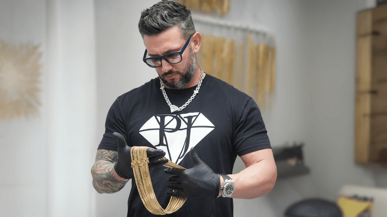 Rafael Perez, founder of Pochy Jewelry, inspects a gold Cuban link chain, symbolizing craftsmanship and innovation in Miami's jewelry industry.