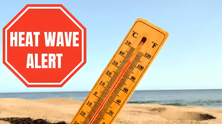 Thermometer displaying high temperatures on a sandy beach with a heat wave alert sign