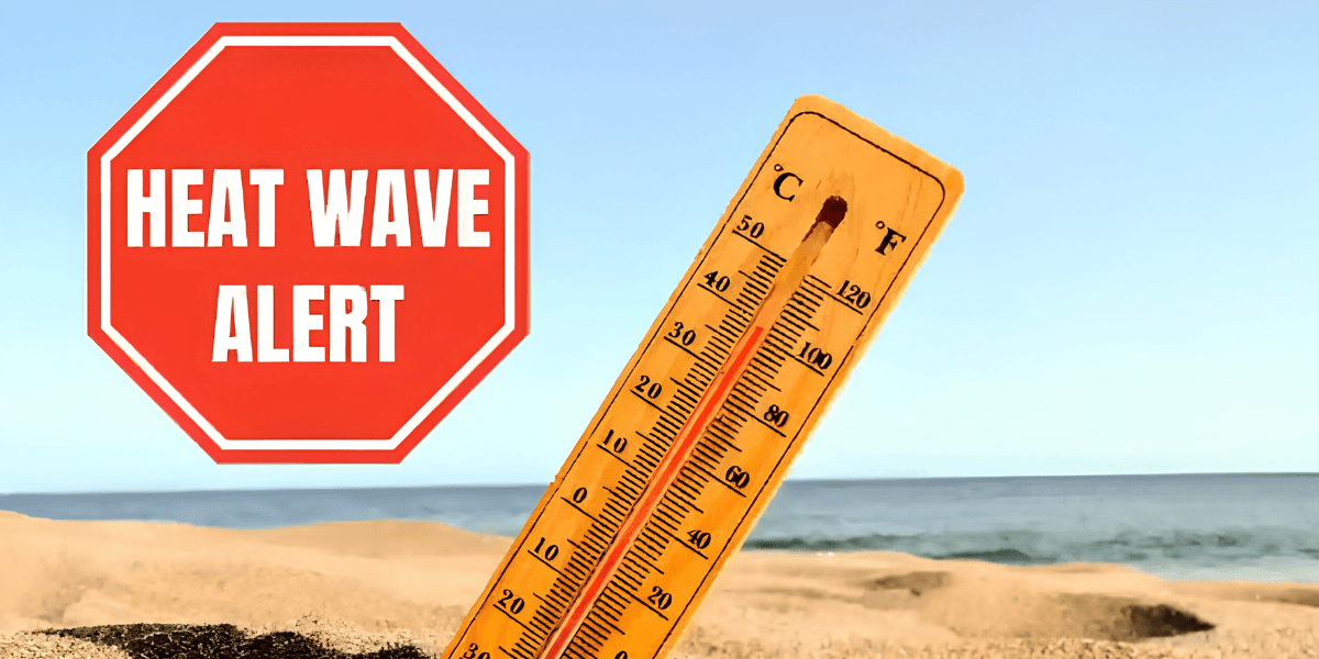 Thermometer displaying high temperatures on a sandy beach with a heat wave alert sign