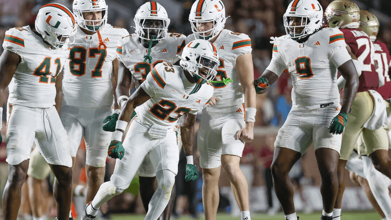 Football players in white jerseys celebrate during a game on the field