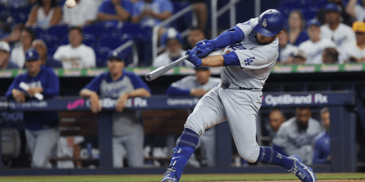 Baseball player in grey uniform swings bat during game with crowd in background