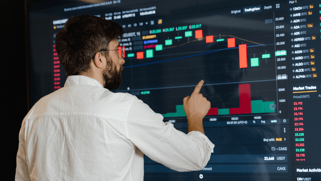 Person analyzing cryptocurrency trading charts on a large digital screen