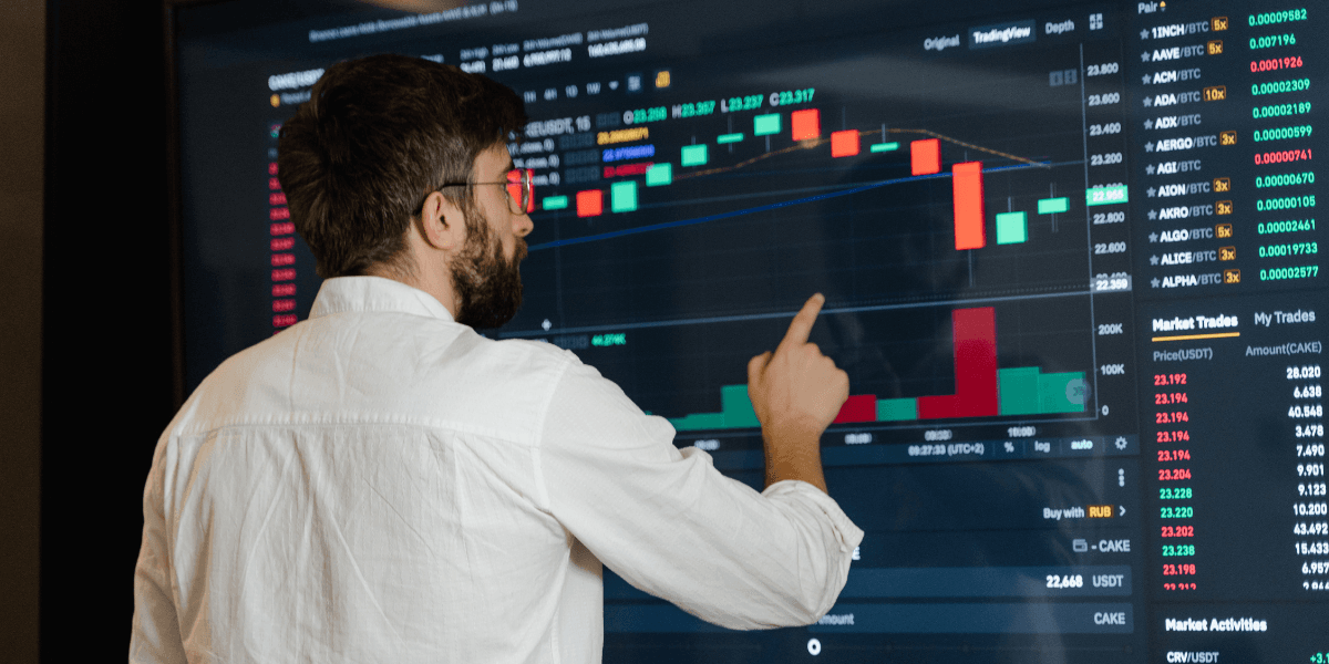 Person analyzing cryptocurrency trading charts on a large digital screen