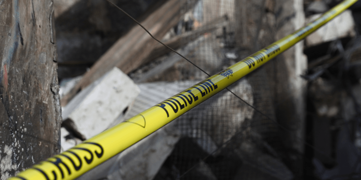 Yellow police tape near a collapsed building with debris scattered around