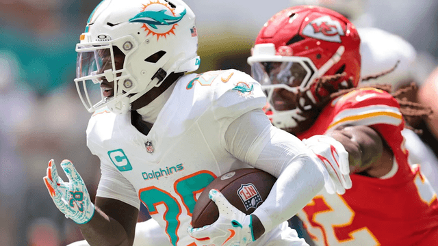 A player in a Dolphins uniform runs with the ball, pursued by a Chiefs defender