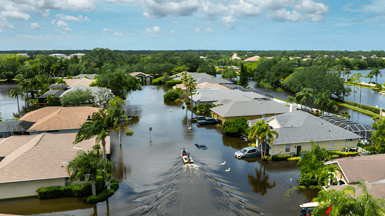 Aerial view of flooded suburban neighborhood with submerged houses and boats navigating the water