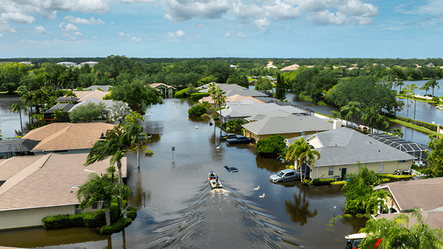 Aerial view of flooded suburban neighborhood with submerged houses and boats navigating the water