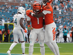 Two Bengals players celebrate a touchdown on the field, while Dolphins players are in background