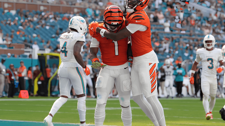 Two Bengals players celebrate a touchdown on the field, while Dolphins players are in background