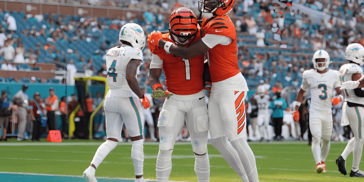 Two Bengals players celebrate a touchdown on the field, while Dolphins players are in background