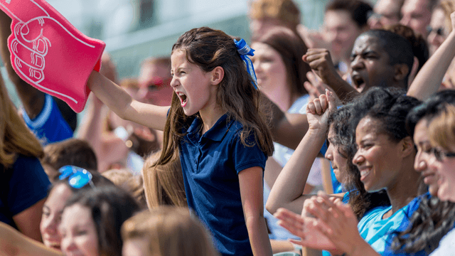 Young soccer fan cheering with a foam finger in a crowded stadium during a match.