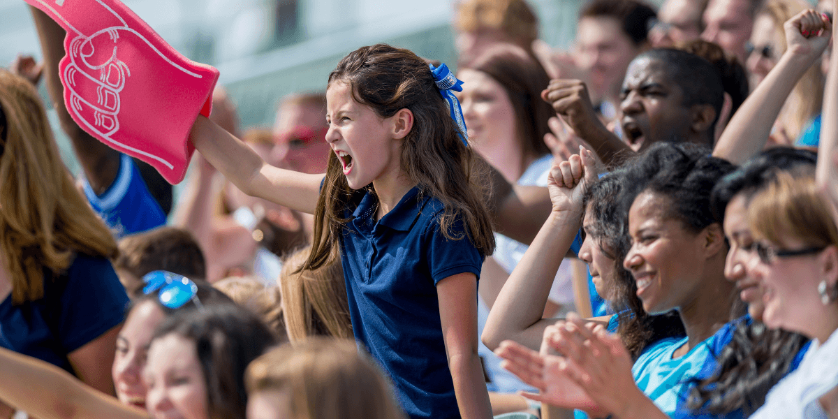 Young soccer fan cheering with a foam finger in a crowded stadium during a match.