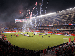 Crowd in stadium celebrating a sports event with fireworks and team presentations on the field