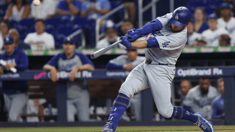 Baseball player in grey uniform swings bat during game with crowd in background