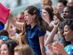 Young soccer fan cheering with a foam finger in a crowded stadium during a match.